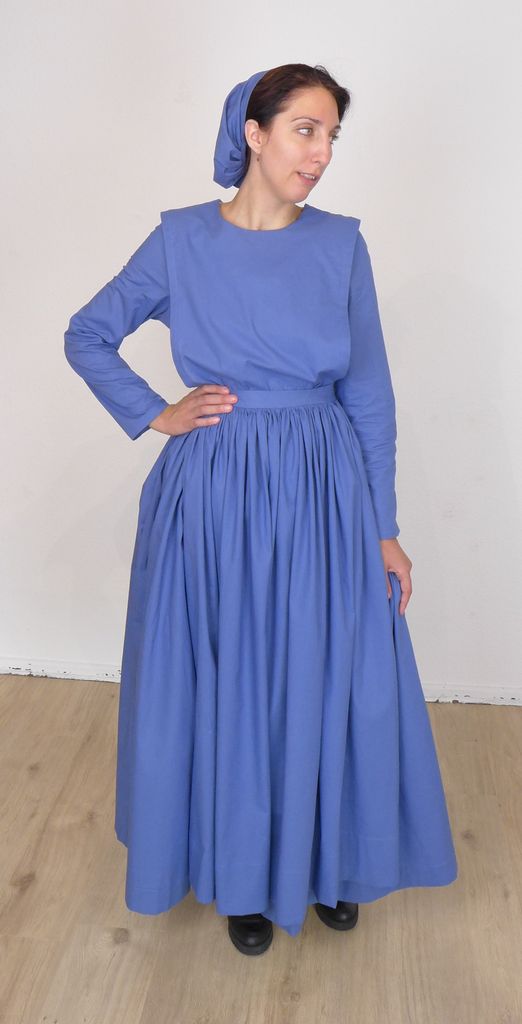 Front view of a standing woman in a plain cape dress