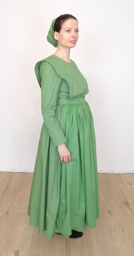 Front view of a standing woman in a plain cape dress