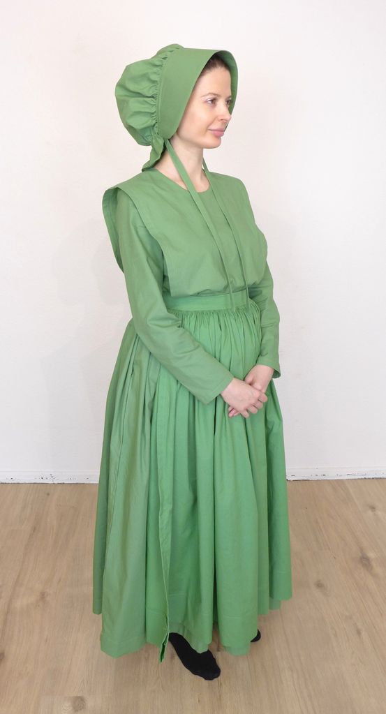 Front view of woman in a plain cape dress wearing a bonnet